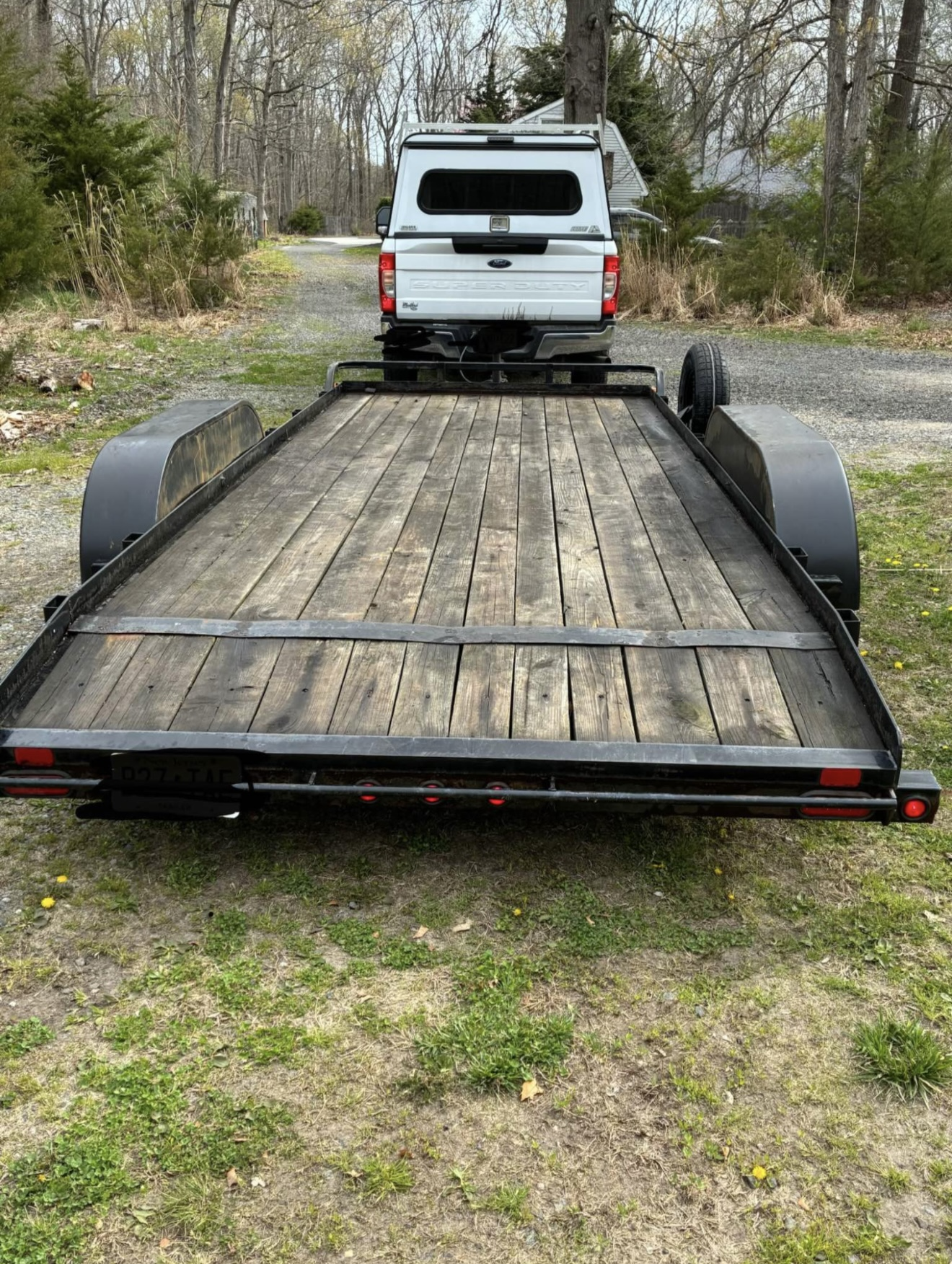 Big Tex 70CH car hauler rear view looking forward along the wood plank deck with Ford Super Duty tow truck ahead